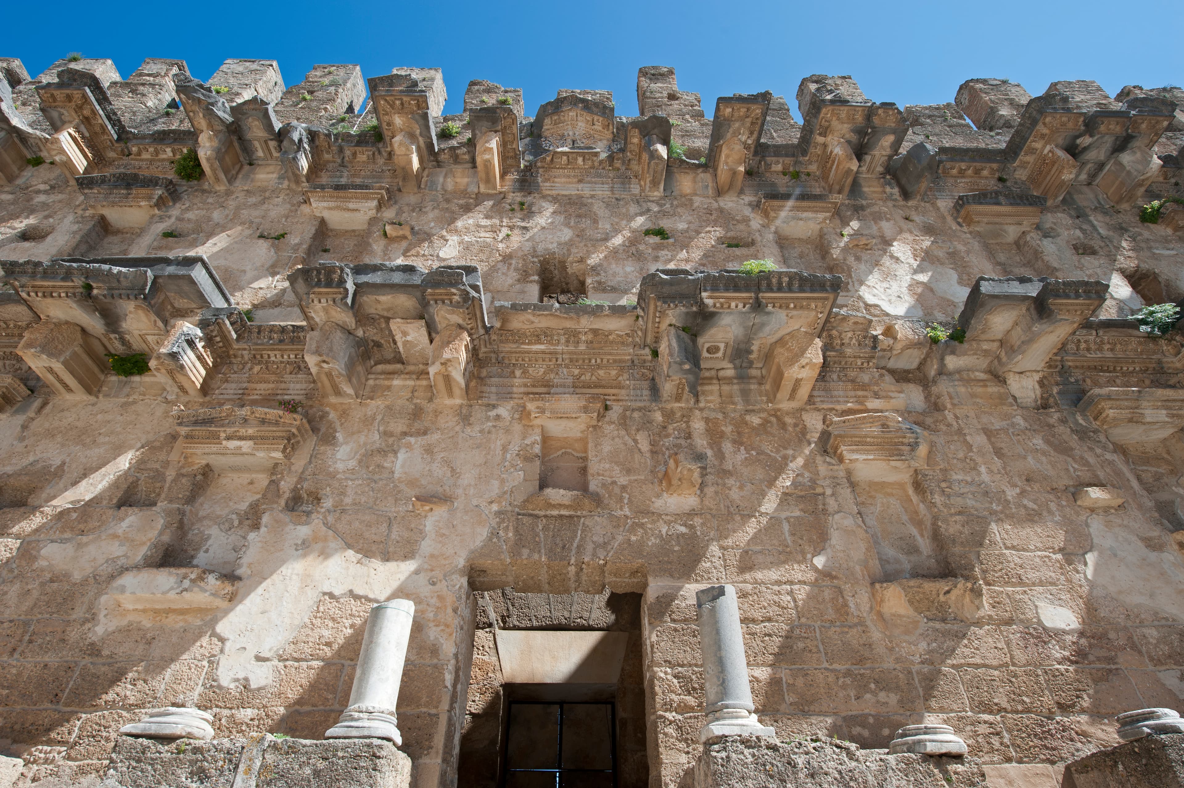 This is one of several pictures taken of the Scaenae frons, the elaborately decorated permanent architectural background of a Roman theatre stage. The photos were captured during multiple visits, some years apart and in different seasons. Although highly detailed, many elements that once adorned the scenae, such as statues, have vanished.