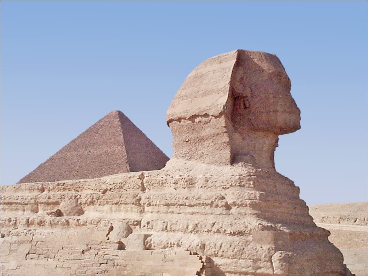 Le Sphinx, avec en arrière-plan la pyramide de Khéops, se trouve à l'entrée de la chaussée qui mène au temple funéraire et à la pyramide de Képhren. Le célèbre Sphinx a été sculpté dans un éperon rocheux sur le plateau de Gizeh, à l'entrée des nécropoles. Long de 57 m et haut de 20 m, il représente un lion à tête d'homme portant la coiffe "némès", probablement celle du pharaon Képhren, dont la pyramide se trouve à proximité.

Cette représentation du roi unit les natures humaines et divines à la force du lion. Le Sphinx est également le seigneur et gardien de la nécropole. Sa datation est incertaine en raison de l'absence d'inscriptions, mais de nombreux spécialistes l'attribuent au règne de Képhren, fils de Khéops (IVe dynastie, 2561-2450 av. J.-C.).

Le visage du Sphinx est très dégradé par rapport à son aspect initial : l'ureus ornant son front a disparu, ainsi qu'une partie du nez et la barbe rituelle, dont certains éléments sont conservés au British Museum. Photo numérique prise par l'auteur en octobre 1998.