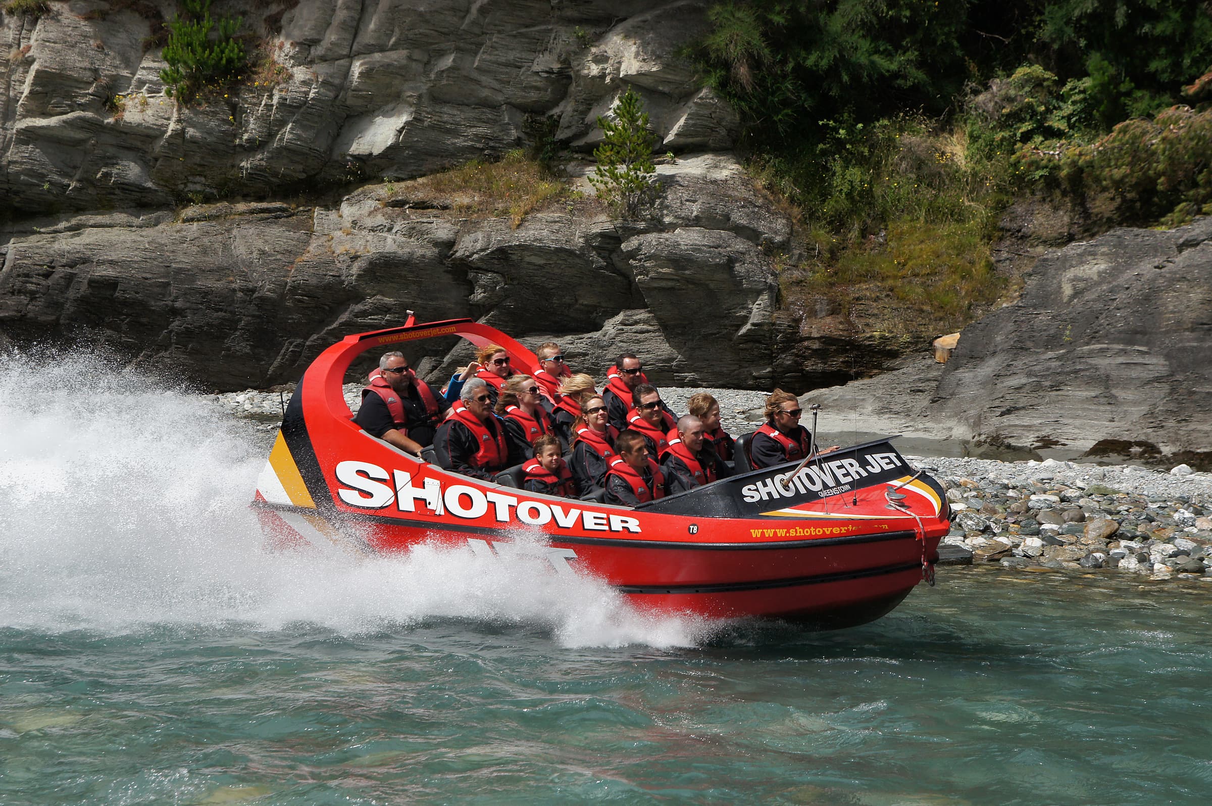 From the moment the accelerator hits the floor, your adrenaline surges as you speed just inches above the water along the famous Shotover River and deep into the spectacular Shotover River Canyons. It’s an incredible white-water ride; the Shotover Canyon walls tower above you while your expert driver maneuvers the ‘Big Red’ Jet Boat with precision, skillfully whipping it past rocky outcrops, skimming around crags and boulders, and racing through the dramatic, narrow canyons. Rock faces blur in your peripheral vision, and the water sprays into a myriad of white water crystals with every turn as you glide in your state-of-the-art ‘Big Red’ Jet Boat at speeds of up to 85 kph over crystal-clear water, as shallow as 10 cm.