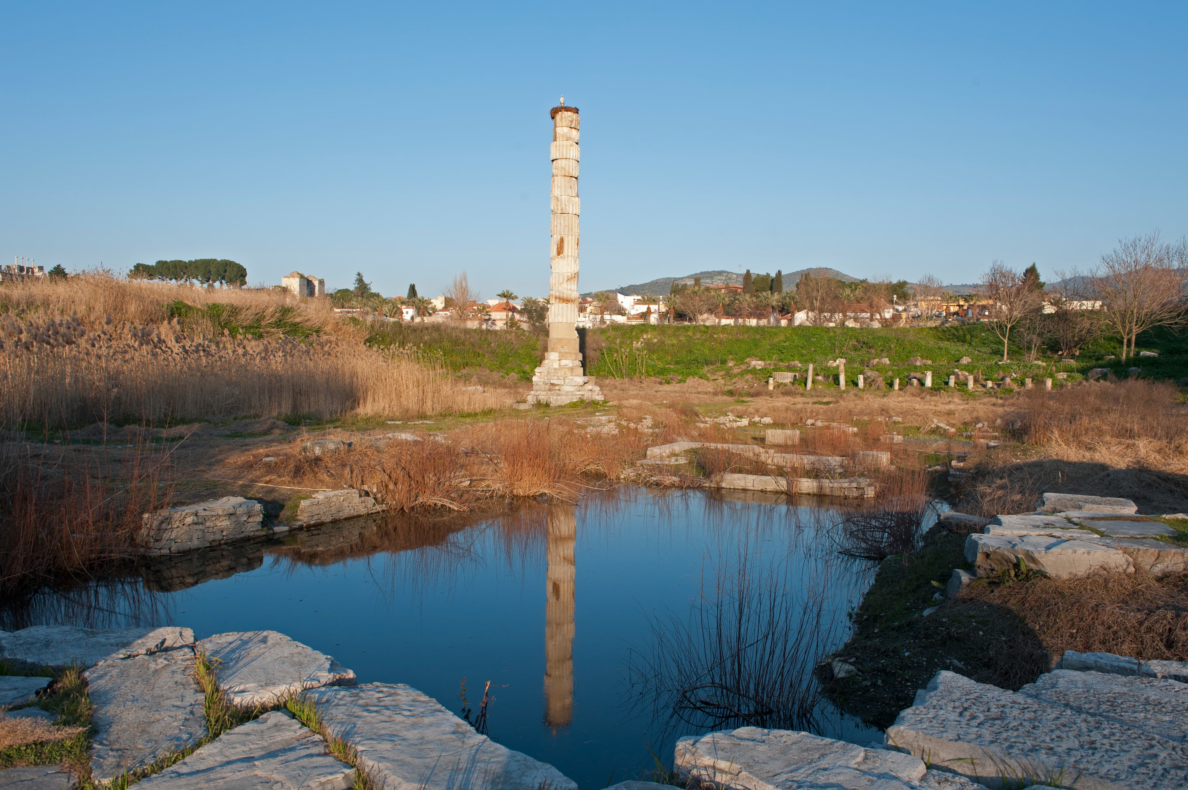 Some pictures show that the terrain is sometimes flooded, while on others, it appears much drier. The Artemis Temple housed the statue of the goddess, which had fallen from the sky and thus could not be touched. Made of dark wood, a curtain would be drawn each morning to reveal the goddess, allowing her to see the gifts brought by her visitors. This temple was one of the Seven Wonders of the World. The great temple was built by Croesus, king of Lydia, around 550 BC, and was rebuilt after being burned by a madman named Herostratus in 356 BC. The Artemesium was famous not only for its immense size (over 350 by 180 feet, approximately 110 by 55 meters) but also for the magnificent works of art that adorned it. The temple was destroyed by invading Goths in AD 262 and was never rebuilt. While little remains of the temple, numerous fragments, especially sculptured columns, can be found in the British Museum. Excavations have revealed traces of both Croesus' temple and the fourth-century structure, as well as three earlier, smaller temples (part of this text from Enc. Brit.).